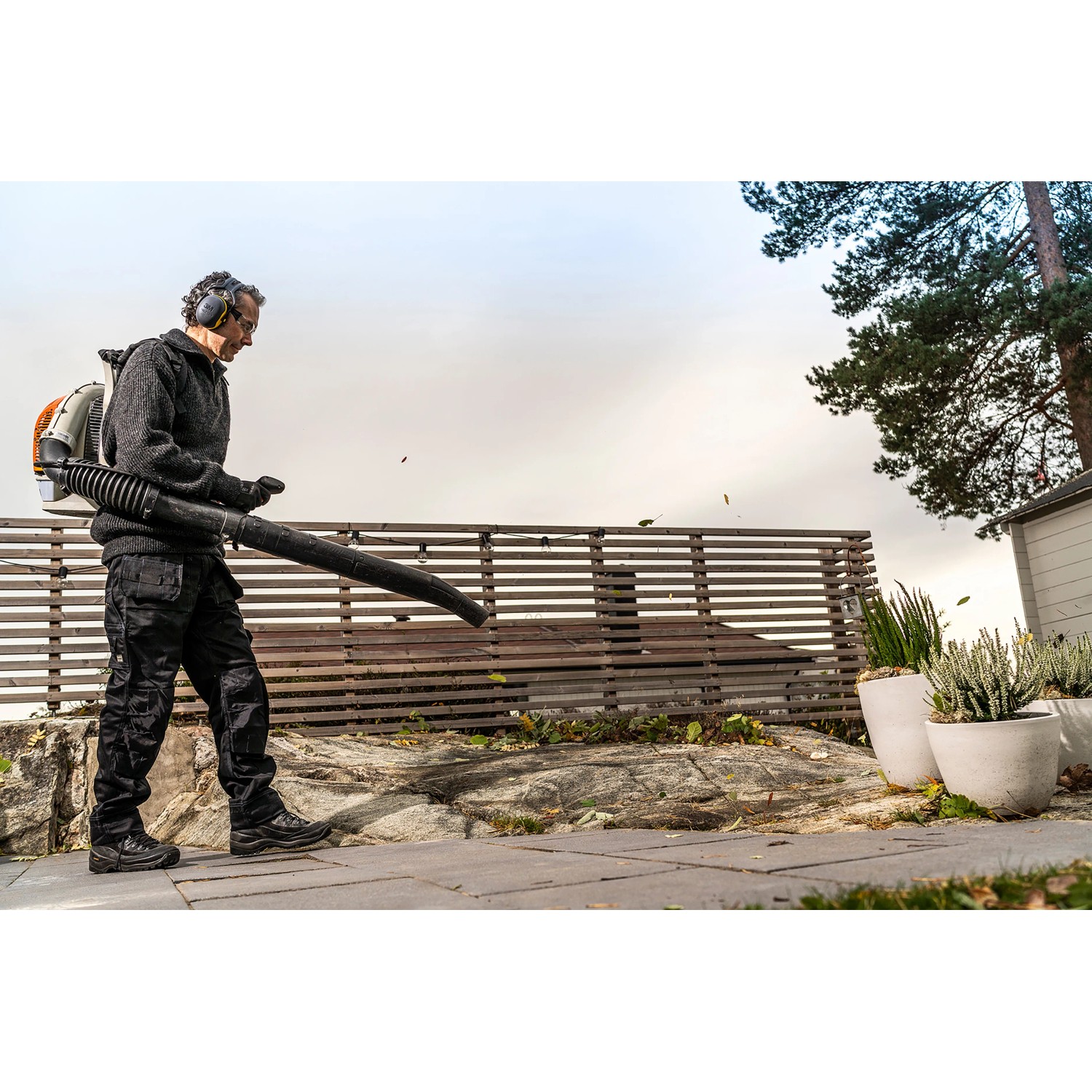 Mann mit 3M Peltor Gehörschutz beim Laubblasen im Garten.