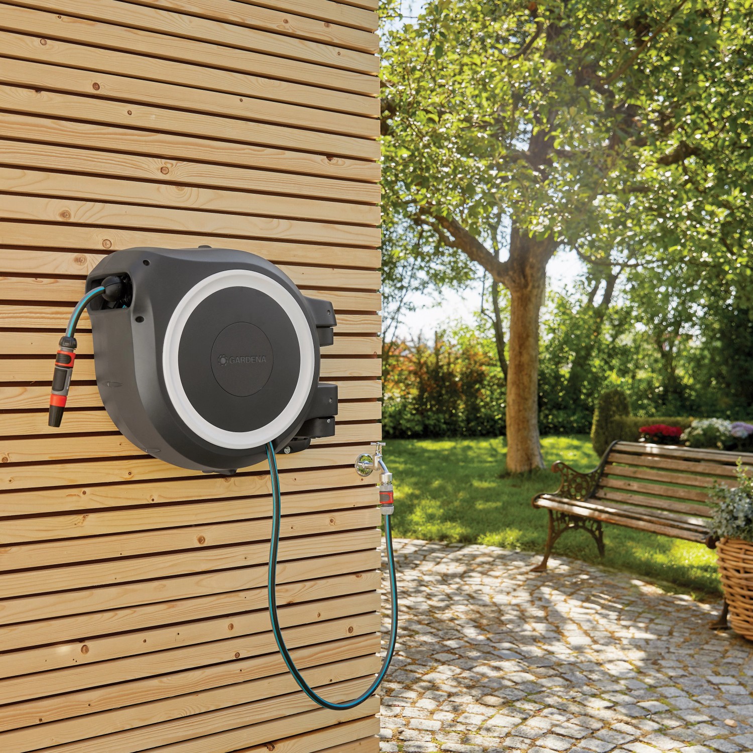 Gardena Wand-Schlauchbox RollUp XL mit 35m Schlauch an Holzwand im Garten.