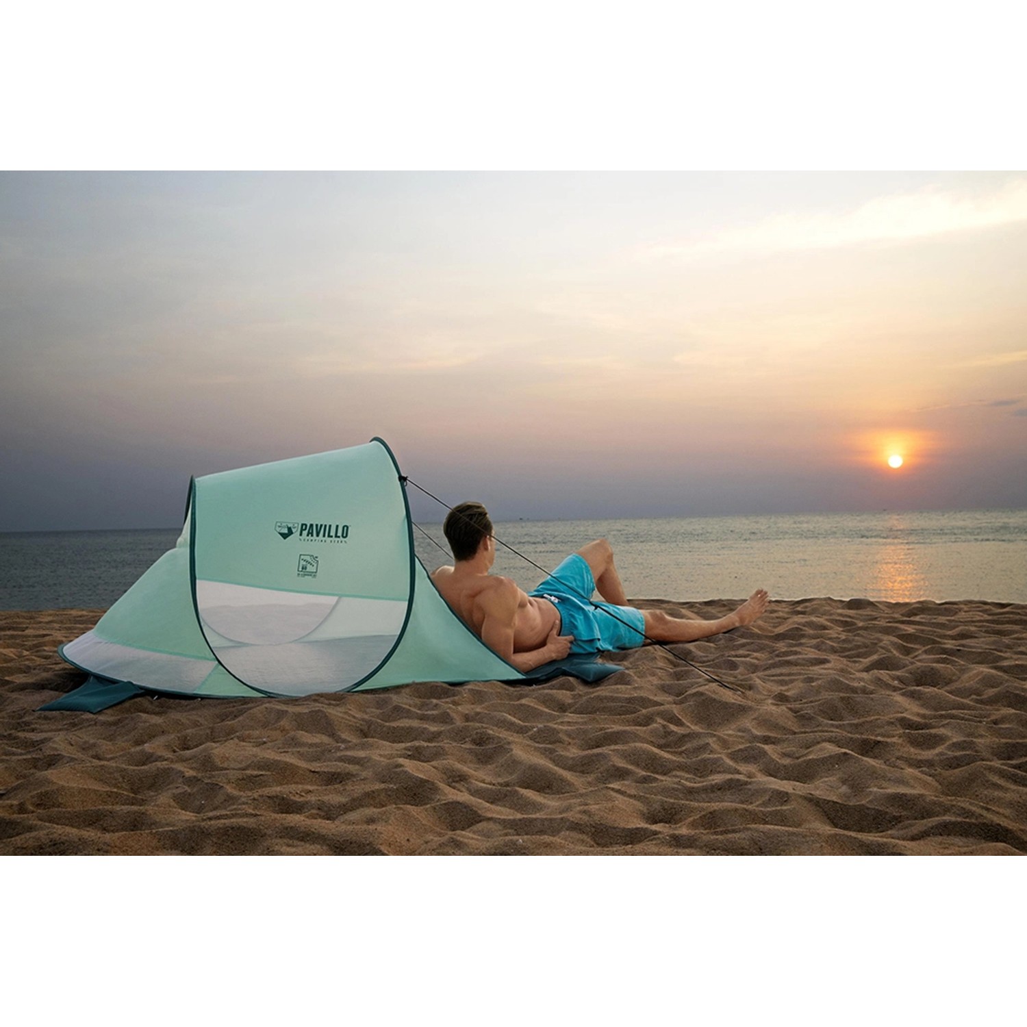 Pavillo Strandmuschel Beach Quick 2 mit Mann am Strand im Sonnenuntergang.