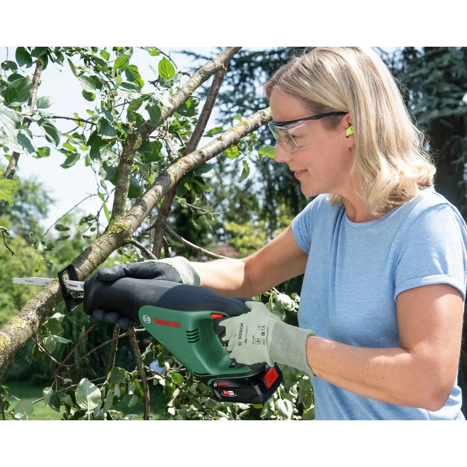 Frau sägt Ast mit Bosch Akku-Säbelsäge AdvancedRecip 18. Stichsäge für Holz- und Metallarbeiten.