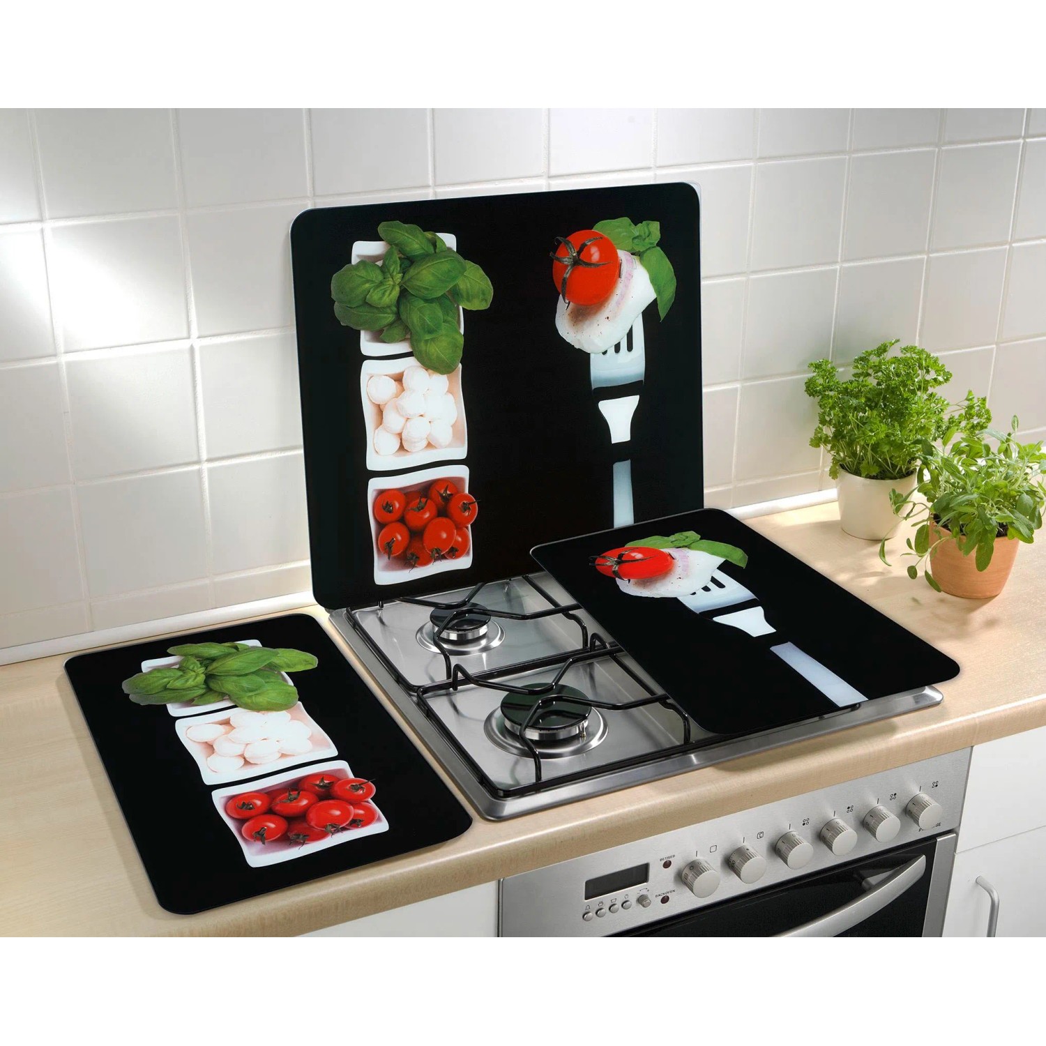 Wenko Herdabdeckplatten Caprese 2er Set auf einem Herd, mit Tomaten, Mozzarella und Basilikum Motiven.
