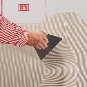 Auftragen von Lugato Designbelagsklebstoff Doppel Plus mit Zahnspachtel auf eine Wand.