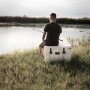 Petromax Kühlbox Sand 50L: Angler sitzt auf der Box am See.