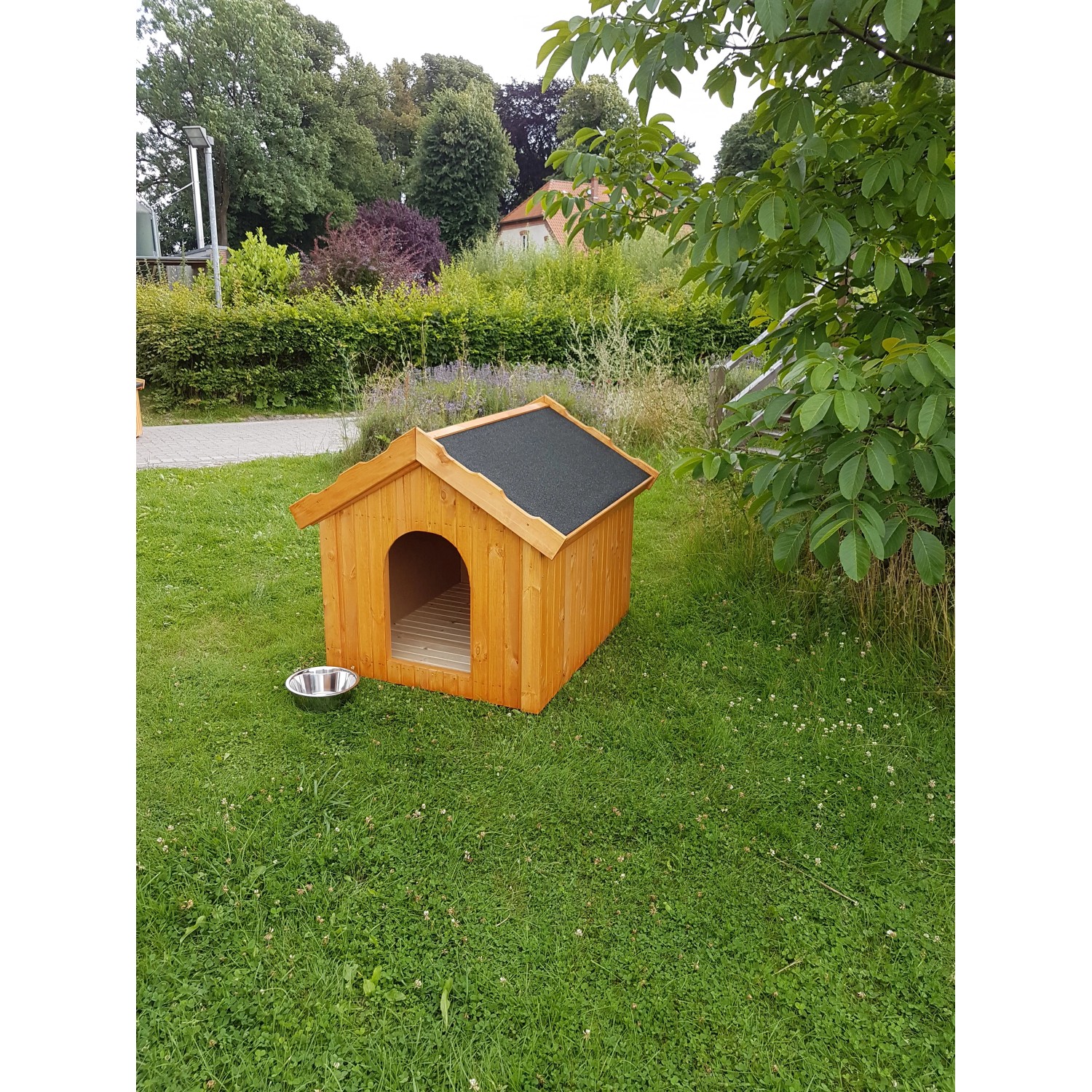 Braune Promadino Hundehütte aus Kiefernholz mit schwarzem Dach und Futternapf im Garten.