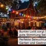 Grüne Partylichterkette mit bunten LED-Tropfenlampen im Biergarten, Weihnachtsbeleuchtung.