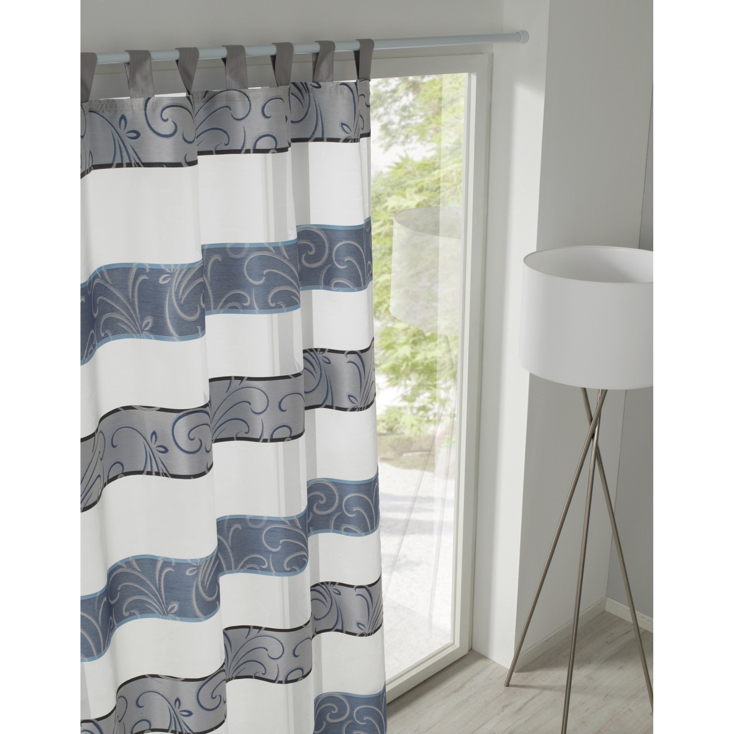 Gardinia Spannstange, weiß, mit grau-blauem Muster am Fenster.