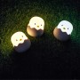 Drei dimmbare MegaLight LED Nachtlichter Eggy Egg in Kükenform auf Rasen.