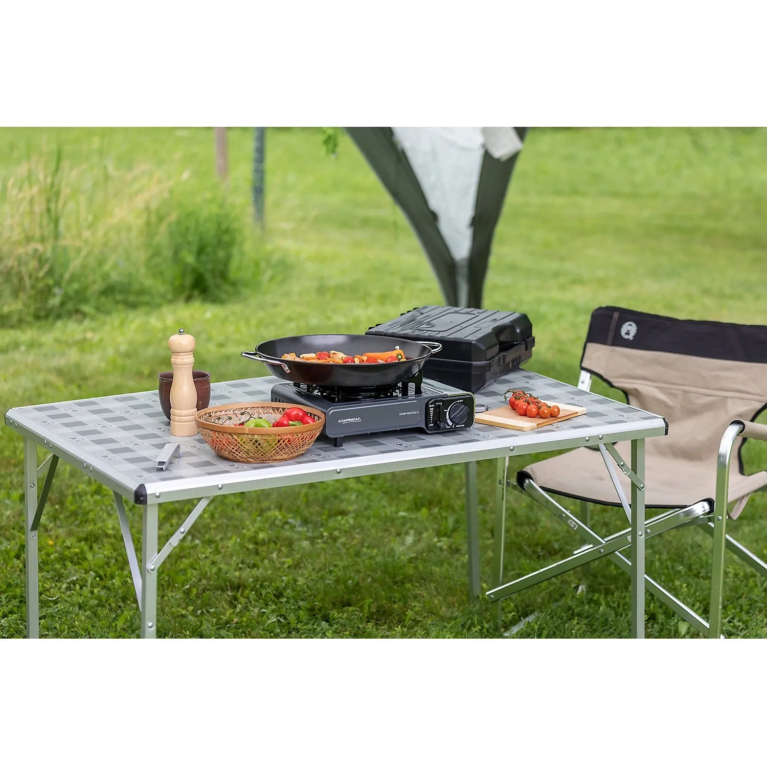 Campingaz Camp'Bistro 3 Tischkocher mit Zubehör auf einem Campingtisch im Freien.