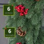 Grüner künstlicher Tannenkranz mit roten Beeren und braunen Tannenzapfen. Detailansicht der Weihnachtsdekoration.