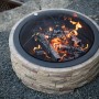 Westmann Feuerstelle in Steinoptik mit Funkenschutzgitter und brennendem Holz.