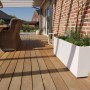 Weißer Vivanno Pflanzkübel Maxi (120x45x45 cm) auf einer Holzterrasse mit Bepflanzung.