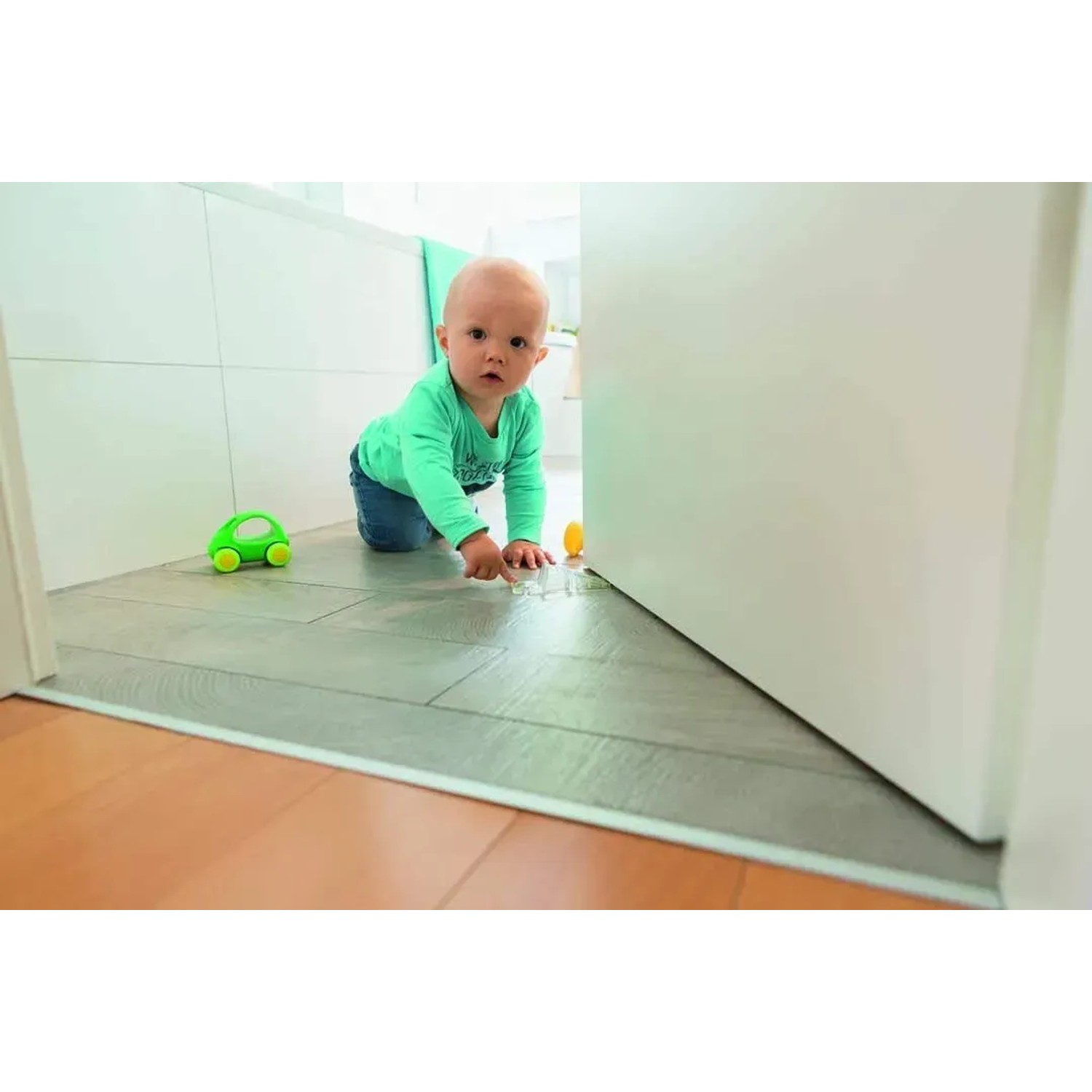 Abus Türstopper JC6200 Luca im Einsatz mit Kind und Spielzeug vor einer Tür.