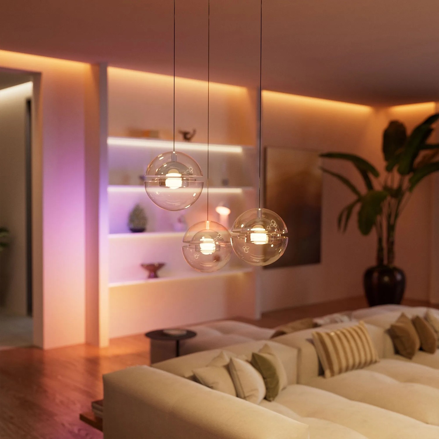 Modernes Wohnzimmer mit drei Hängelampen und farbiger, smarter Beleuchtung, passend für Philips Hue Systeme.