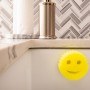 Gelber Scrub Daddy Schwamm mit Smiley im Spülbecken, befestigt mit dem Caddy Halter.