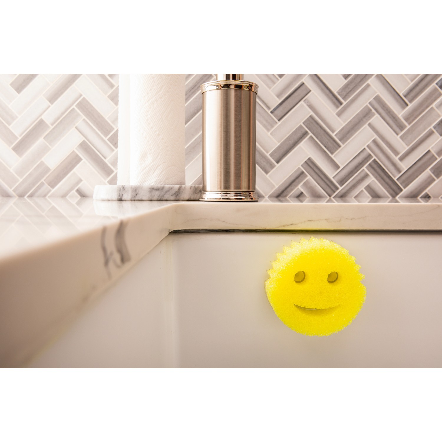 Gelber Scrub Daddy Schwamm mit Smiley im Spülbecken, befestigt mit dem Caddy Halter.