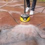 Kärcher Flächenreiniger T 7 Plus T-Racer im Einsatz auf einer Terrasse. Der gelb-schwarze Terrassenreiniger säubert Steinplatten.