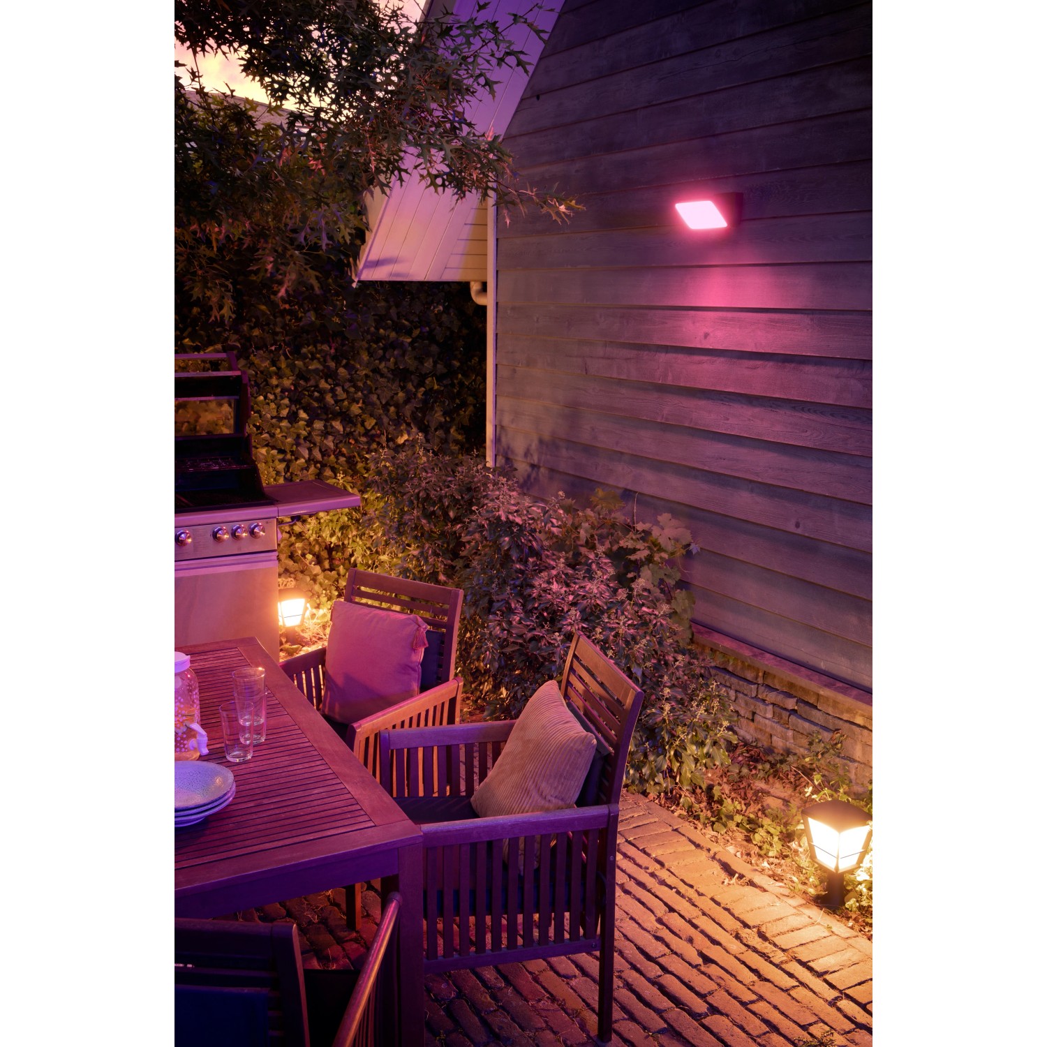 Philips Hue Econic LED-Sockelleuchte im Garten mit farbiger Beleuchtung.