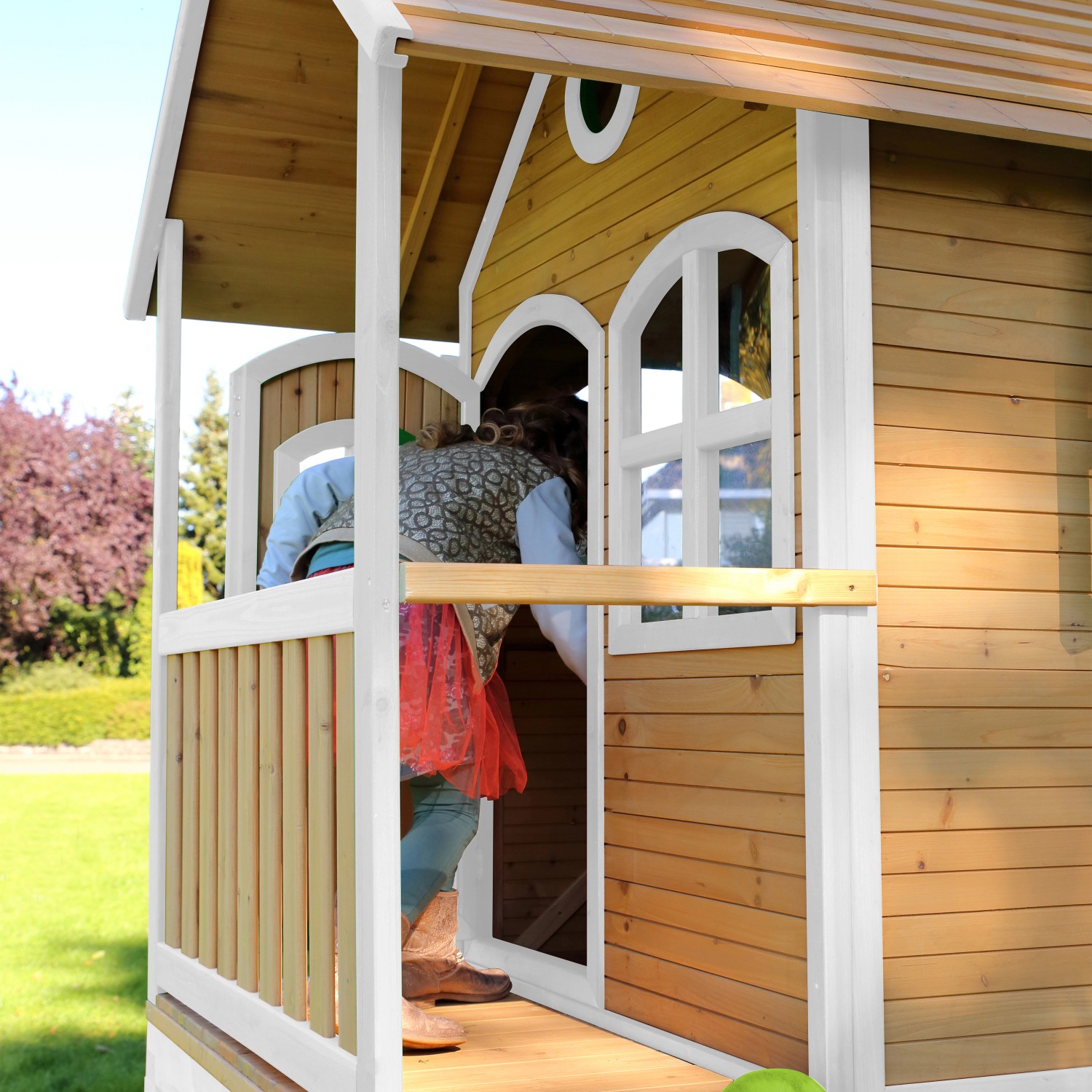 Axi Spielhaus Laura mit Rutsche, braun/weiß, mit Veranda und Fenstern. Kind betritt das Haus.