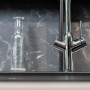 Verchromte VIZIO 3 Wege Küchenarmatur mit schwenkbarem Auslauf vor dunkler Marmorwand.