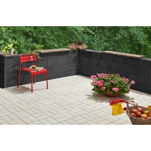 Anthrazitfarbene Mini-Pflanzsteine als Gartenmauer und Beetbegrenzung mit rotem Stuhl und Blumen.