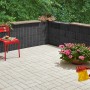 Anthrazitfarbene Mini-Pflanzsteine als Gartenmauer und Beetbegrenzung mit rotem Stuhl und Blumen.