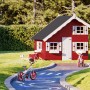 Rotes Palmako Spielhaus Tom aus Fichtenholz mit zwei Ebenen und weißen Fensterläden im Garten.