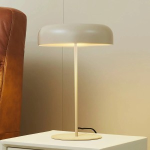 Moderne Lindby Edion Tischlampe aus beigem Metall mit rundem Schirm, leuchtend auf einem Beistelltisch. Für Wohnzimmer.