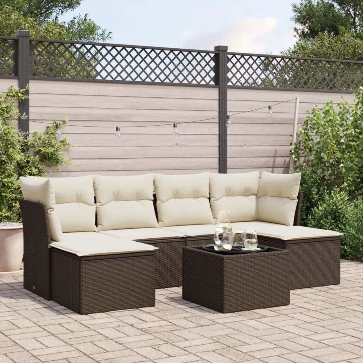 Braune 7-teilige Garten-Sofagarnitur aus Rattan mit cremefarbenen Kissen und Tisch.