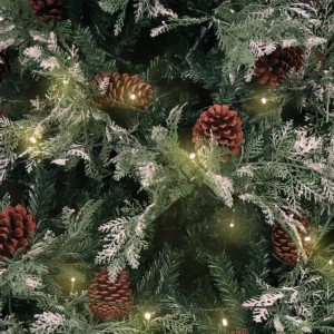 Detailaufnahme: Grüner, künstlicher Weihnachtsbaum mit Schnee, Kiefernzapfen und warmweißen LEDs.