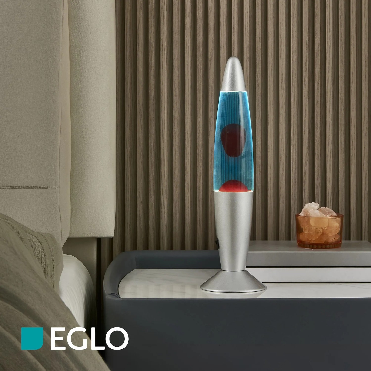 Klassische Eglo LED-Lavatischleuchte in Silber mit blauer Flüssigkeit und rotem Wachs auf Nachttisch.