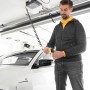 Mann lädt E-Auto mit Schellenberg Spiralkabel am Garagentorantrieb. Praktische Stromversorgung in der Garage.