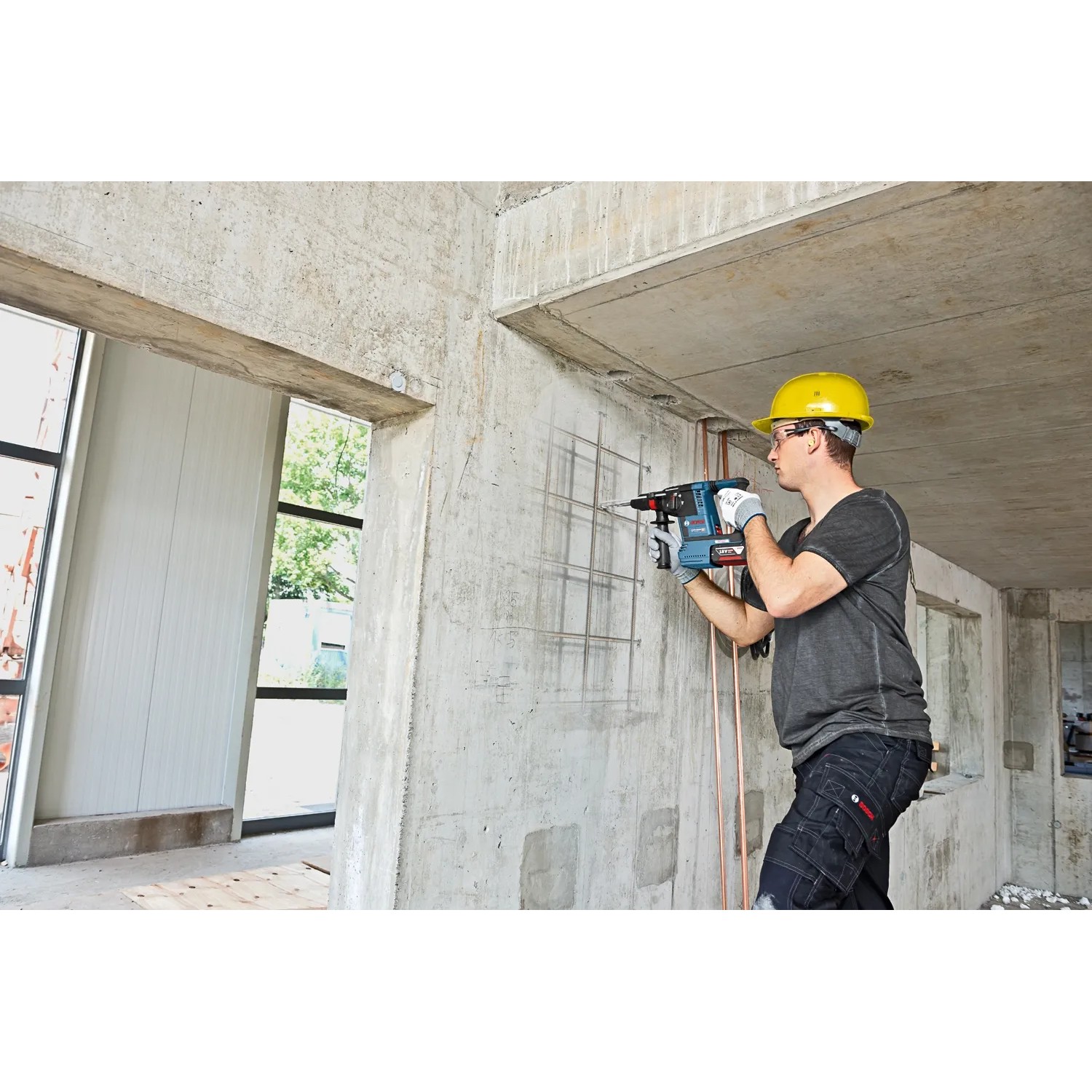 Handwerker bohrt mit dem Bosch Akku-Bohrhammer GBH 18V-26 in Betonwand. Teil des Bosch Professional Combi-Kit.