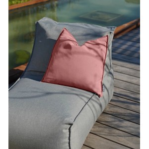 Korallefarbenes mokebo Outdoor Kissen 'Die Auszeit' 45x45 cm auf grauer Gartenliege.