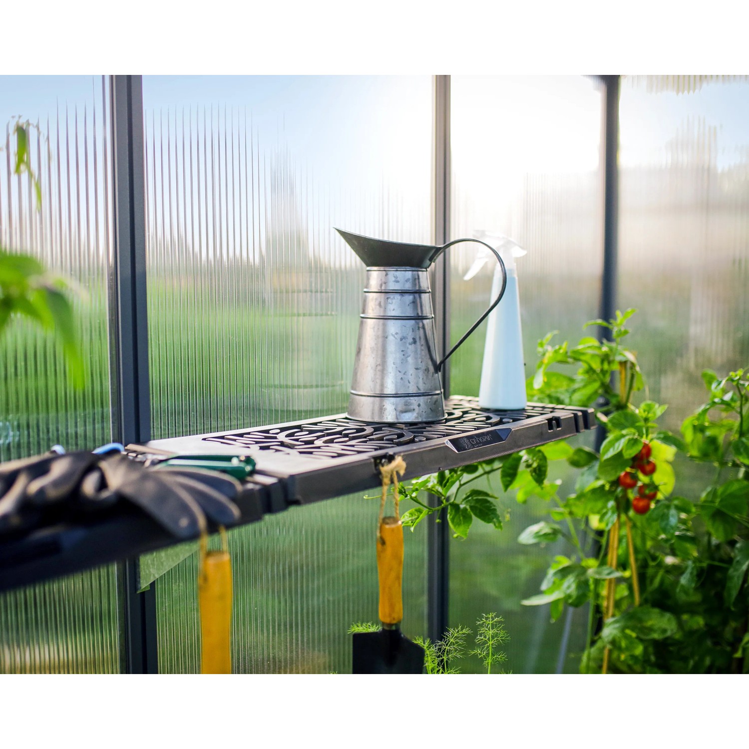 Palram Canopia Gewächshaus Regalset mit Gießkanne und Gartengeräten auf einem der drei Regalböden.