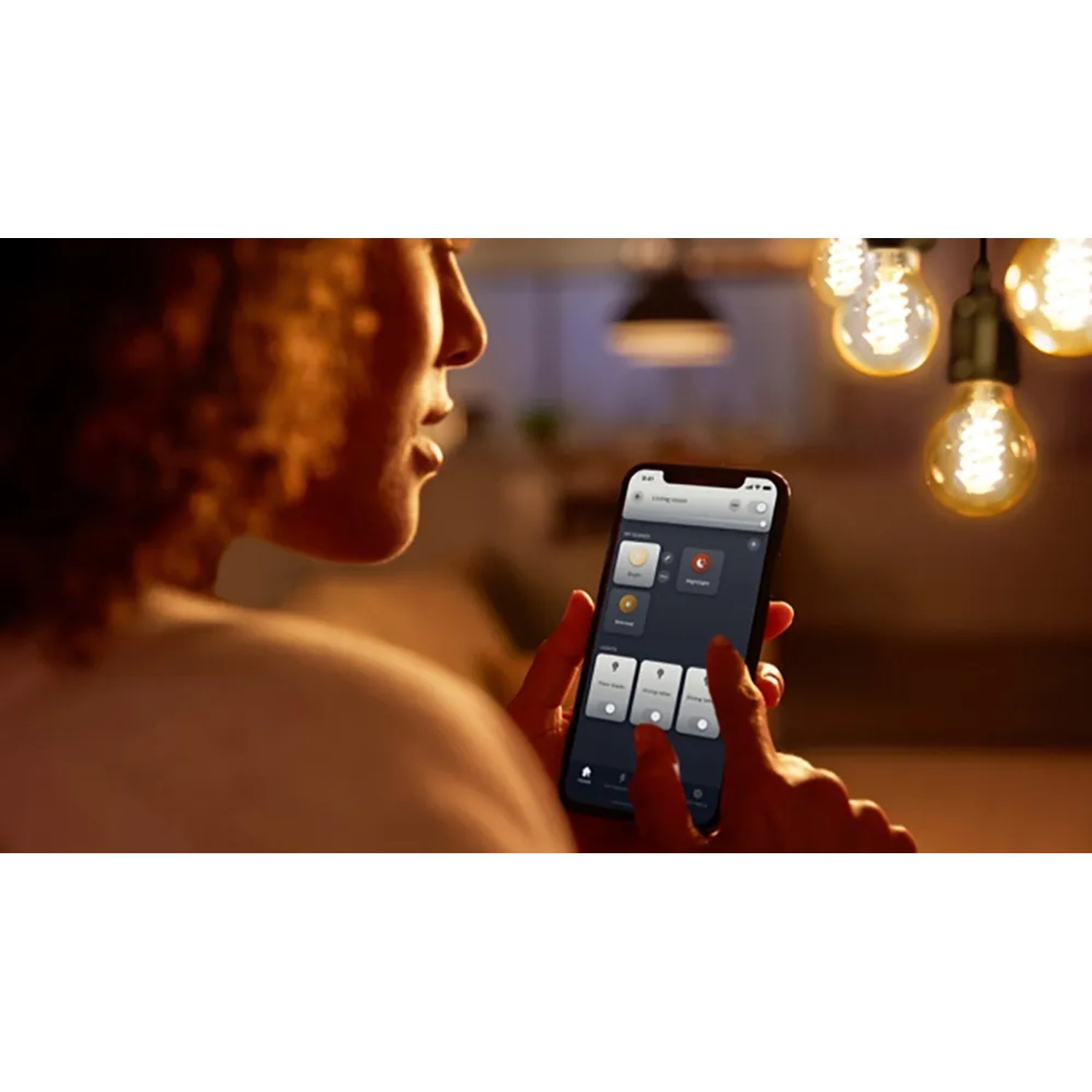 Frau steuert Philips Hue Filament Lampe per App. Vintage-Look, dimmbar, warmweiß bis kaltweiß.