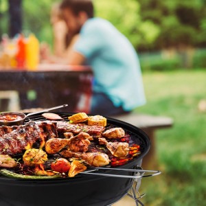 Schwarzer Relaxdays Holzkohle Kugelgrill mit Grillgut wie Rippchen und Gemüse im Freien. Ideal für Picknick und BBQ.