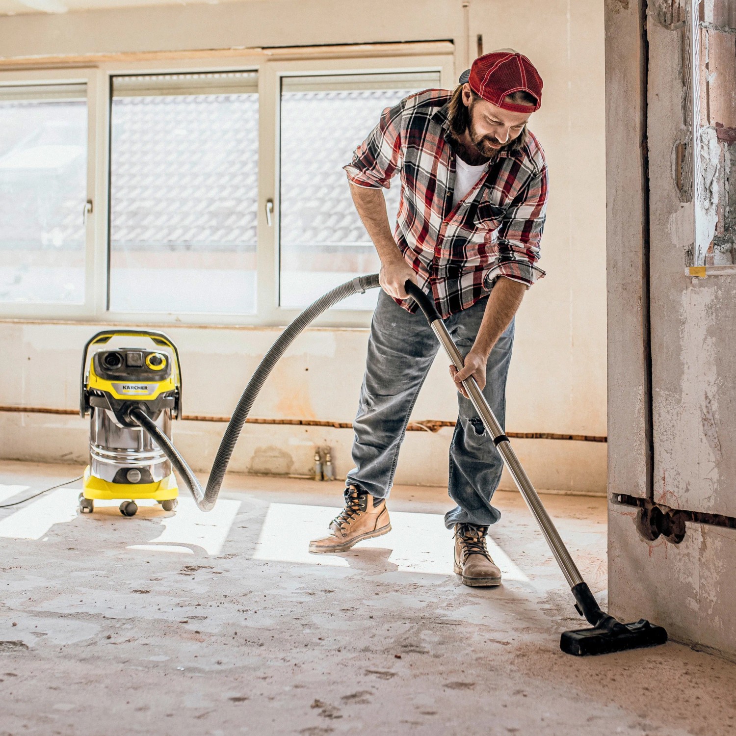 Mann saugt mit Kärcher Nass-Trockensauger WD 6 P S V-30/6/22/T eine Baustelle.