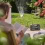 Gardena Haus- und Gartenautomat 5000 Silent Comfort im Einsatz mit Rasensprenger im Garten.