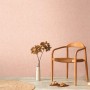 Rosa Vliestapete in Textiloptik von AS Creation, passend zu Wohnambiente mit Holzstuhl und Deko.
