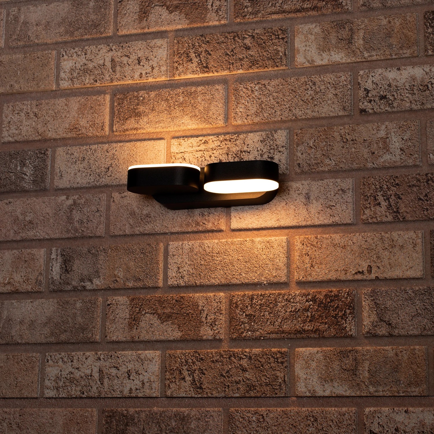 Schwarze LED`s light Außenwandleuchte Oval mit 340° Drehung an einer Backsteinwand.