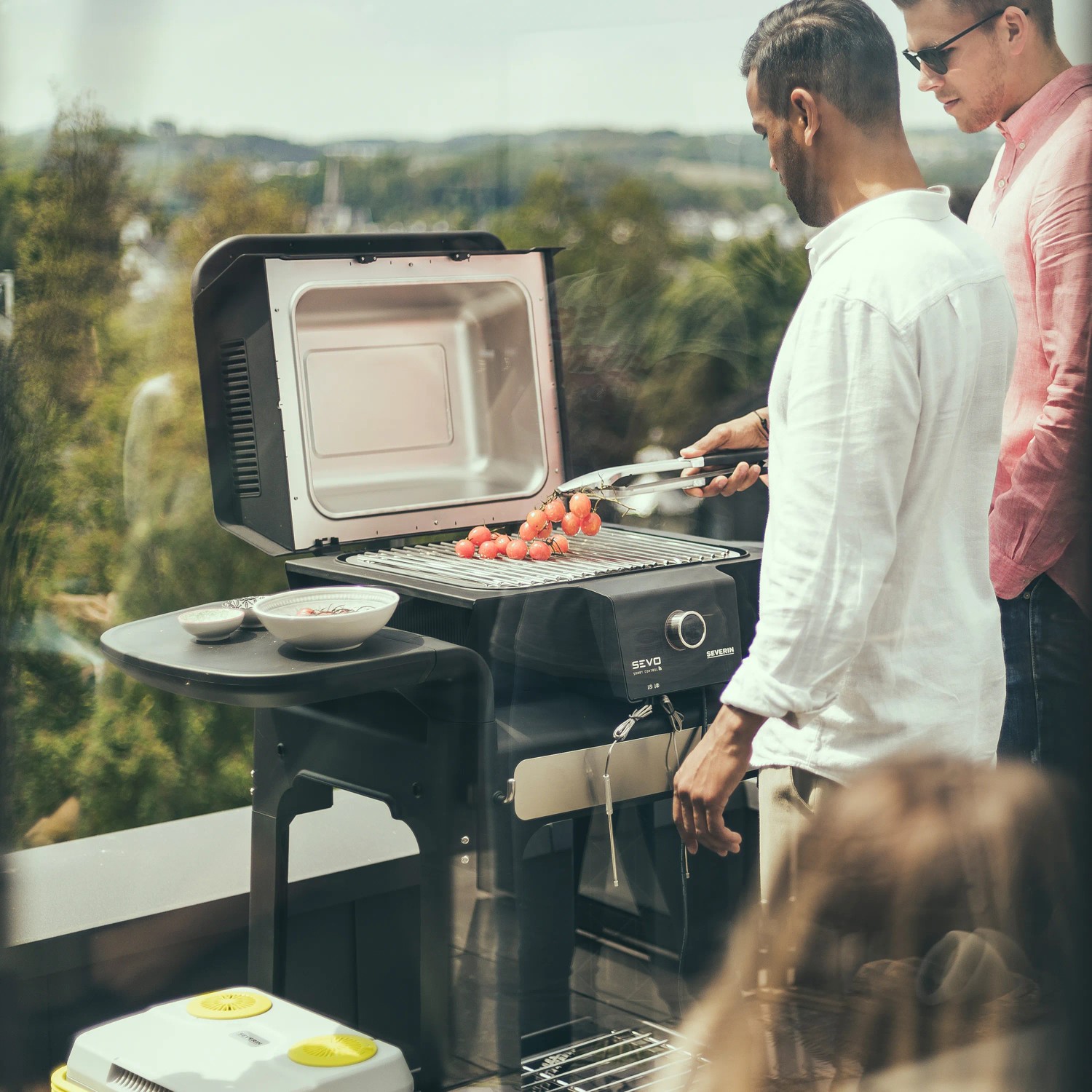 Severin Standgrill PG 8139: Elektrogrill mit Grillgut und zwei Personen im Garten.