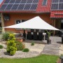 Cremeweißes Toldoro Sonnensegel Dreieck 5x5x5m über Terrasse mit Gartentisch und Stühlen.
