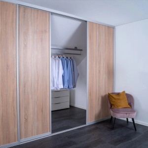 Schiebetür-Baupaket mit Dekor Eiche Geplankt und silbernen Profilen, eingebaut in einem begehbaren Kleiderschrank.