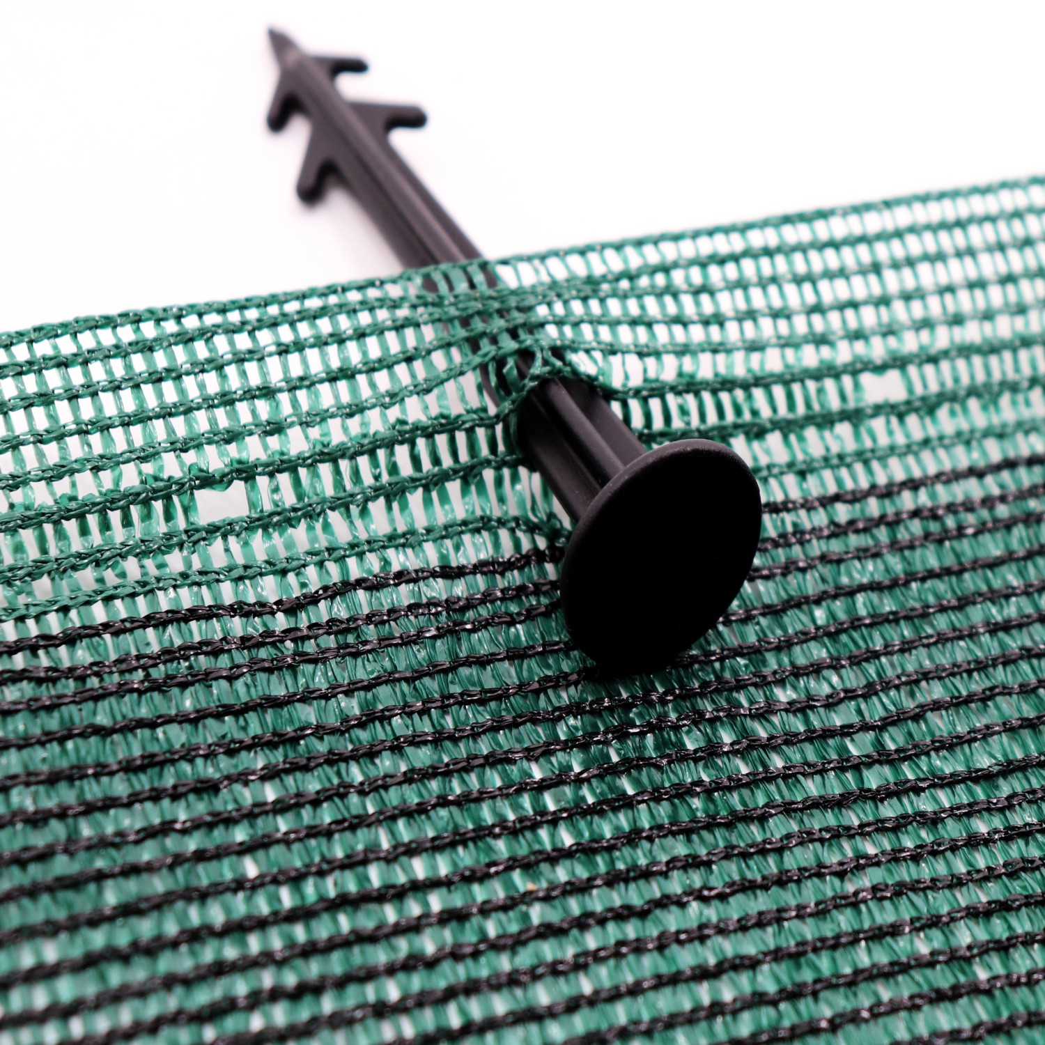 Detailaufnahme eines grünen Aquagart Maulwurfnetzes mit Erdanker zur Befestigung.