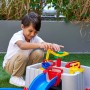 Junge spielt mit AquaPlay Wasserbahn Harbour (63-tlg.). Bunte Wasserbahn mit Booten und Kran im Garten.