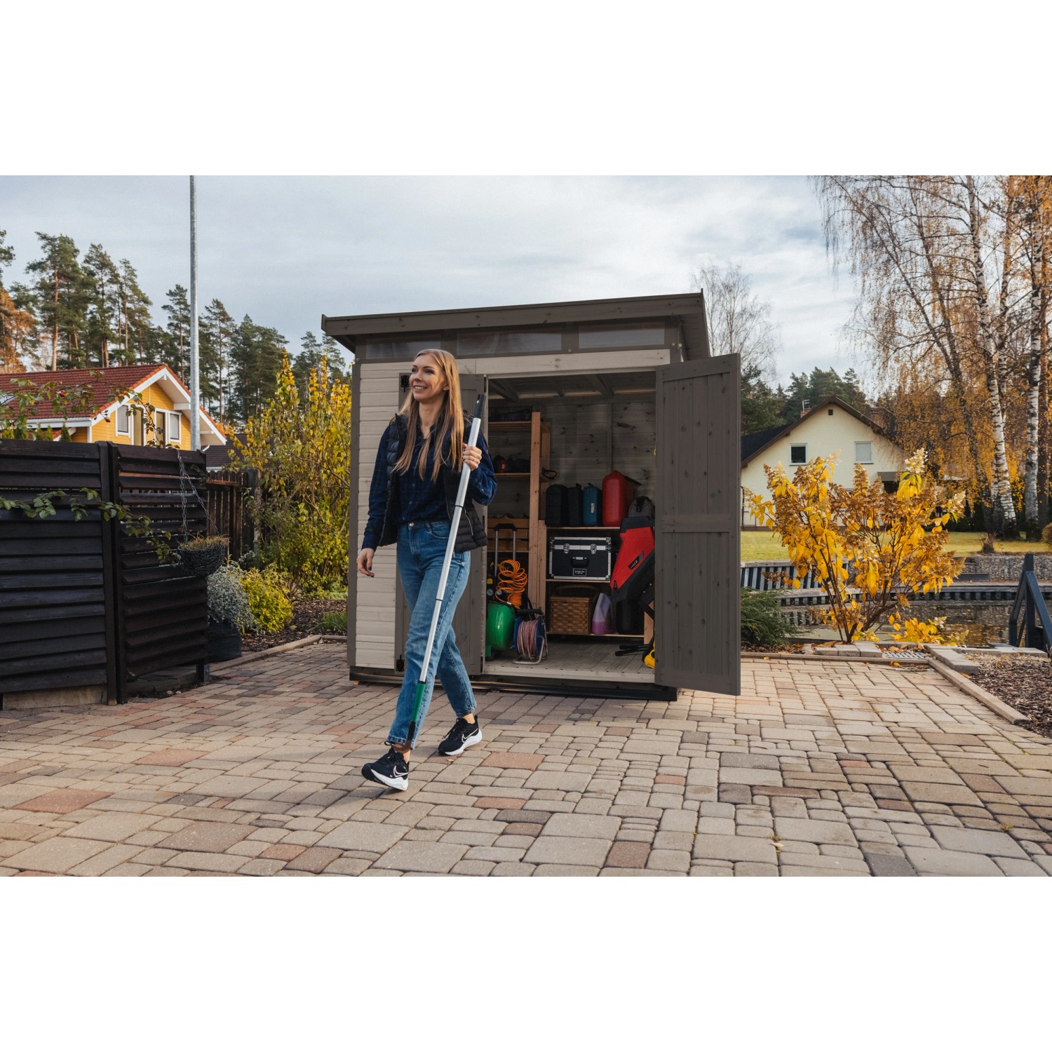 Graues Upyard Gartenhaus Strongbox L mit geöffneten Doppeltüren und einer Frau davor.