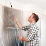Mann streicht Decke mit Tesa Easy Cover Universal Abdeckmaterial, 2er-Pack.
