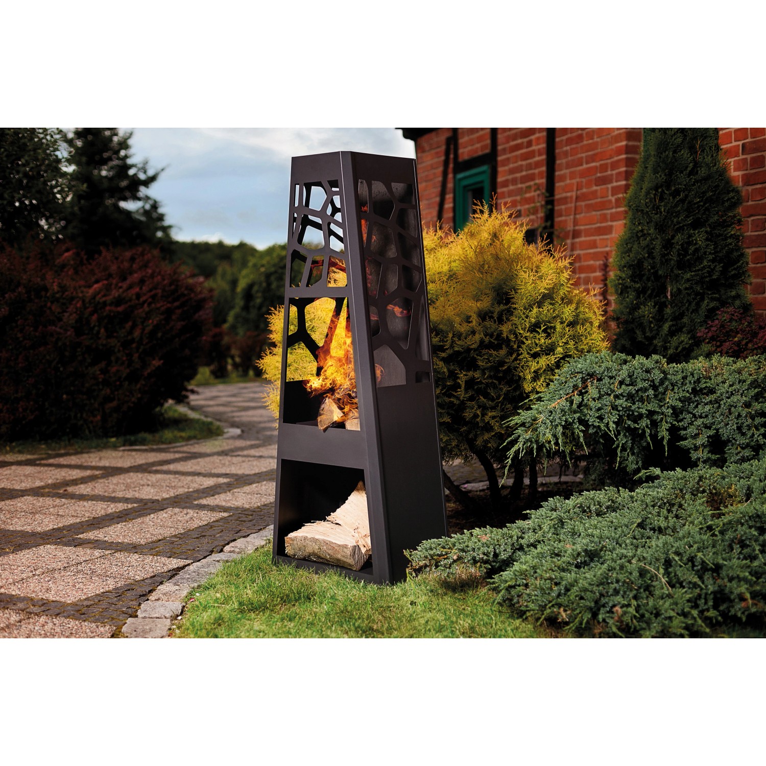 Schwarzer Dobar Metall Gartenkamin mit Holzscheit-Lagerung und offenem Feuer im Garten.
