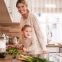 Frau und Kind bereiten Essen in der Küche zu. Verschiedene Zutaten liegen auf der Arbeitsfläche.