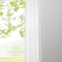 Mydeco Schlaufenschal Pure Weiß, 245x135 cm, halbtransparent vor Fenster mit Ausblick ins Grüne.